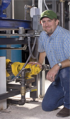 Figure 1. Scott Johnson, president of GEN-X Energy Group, kneels next to one of the many Blackmer ProVane motor speed sliding vane pumps located in the plant.