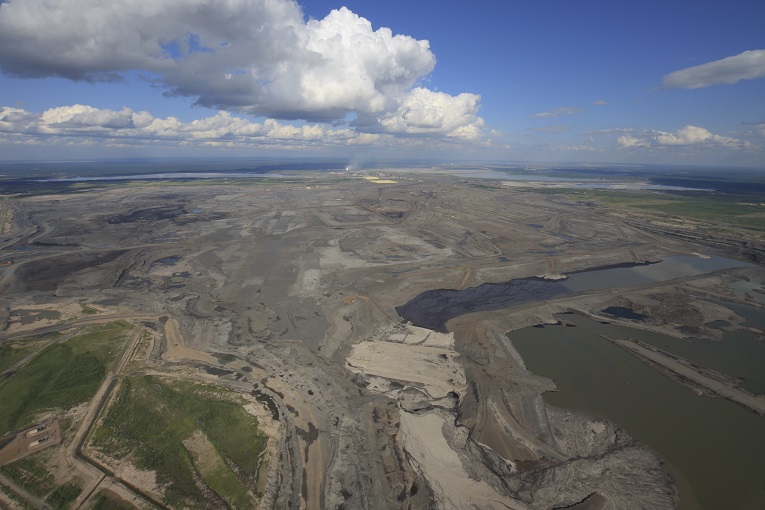 A wide view of an open pit bitumen mining operation in northern Alberta. Large stockpiles of the by-product sulfur (yellow) can be seen in the background. (Image: Donny Ash/Shutterstock)
